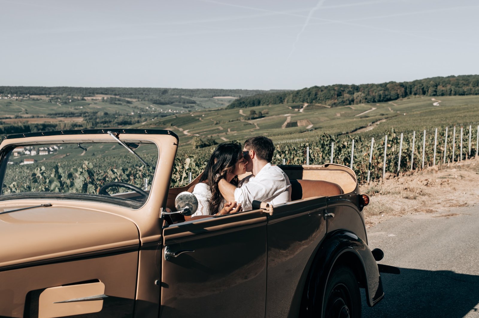 Couple installé dans la Peugeot 301 D au milieu des vignes